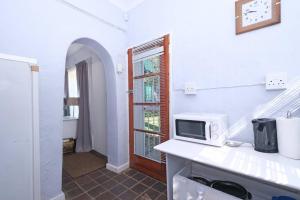 eine weiße Küche mit einer Mikrowelle auf der Theke in der Unterkunft Sun Garden Cottage in Johannesburg