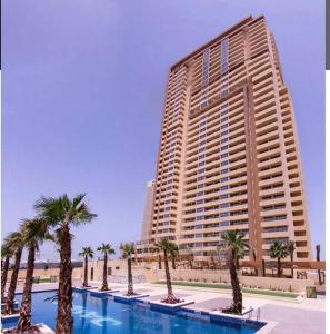 un gran edificio con palmeras frente a una piscina en Ghalia Damac Studio Apartment, en Dubái