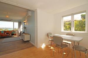 a dining room with a table and chairs and a window at Classic bach near the beach in Oneroa +14 photos