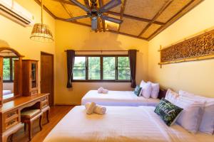 a bedroom with two beds and a desk and a desk at The Parrot Inn Kanchanaburi in Kanchanaburi City