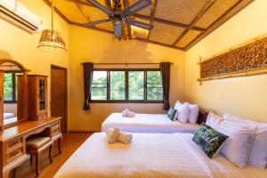 a bedroom with two beds and a desk and a desk at The Parrot Inn Kanchanaburi in Kanchanaburi
