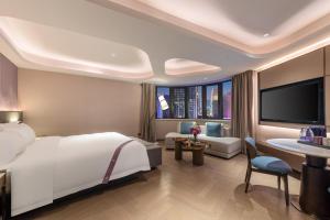 Imperial Traders Elong Hotel في قوانغتشو: غرفة نوم بسرير كبير وغرفة معيشة