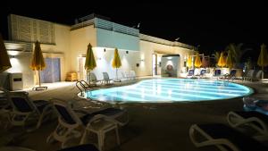 a swimming pool at night with chairs and umbrellas at Holy Family Hotel in Jabal aţ Ţayr