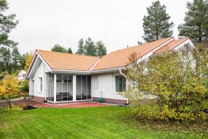 a white house with an orange roof and a yard at Villa Nordic Rovaniemi in Rovaniemi