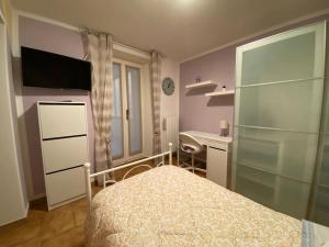 Schlafzimmer mit einem Bett, einem Schreibtisch und einem TV in der Unterkunft Ca’Lina,autentico alloggio spazioso con posto auto in Lecco