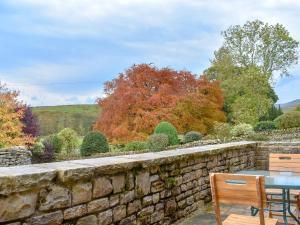a stone wall with a table and chairs and trees at The Stable - Uk10271 in Appersett