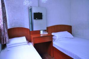 a room with two beds and a mirror and a tv at Jinhai Hotel in Hong Kong