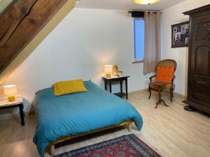 um quarto com uma cama azul e uma cadeira em Chez Rosa em Haguenau