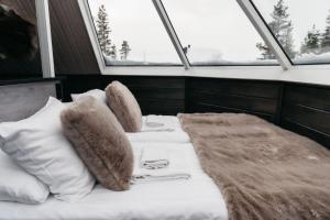 un letto in una camera con cuscini e coperta di Northern Lights Village Pyhä a Pyhätunturi