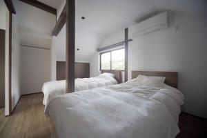 um quarto com 2 camas com lençóis brancos e uma janela em Nesoberi　VILLA TAKASU em Kanoya