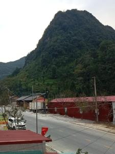 uma estrada com uma montanha ao fundo com um carro em New Homestay em Ha Giang