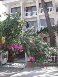 a woman standing in front of a building with pink flowers at Carikci Hotel in Marmaris