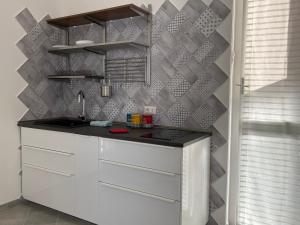 a kitchen with white cabinets and a gray wall at My Blue at Milano Mind in Pero