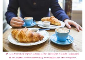 a person sitting at a table with cups of coffee and croissants at Archimede's Rooms in Syracuse