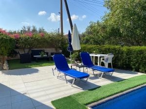 twee blauwe stoelen en een tafel en parasol naast een zwembad bij Paphos Apartment with Private Pool in Mesoyi
