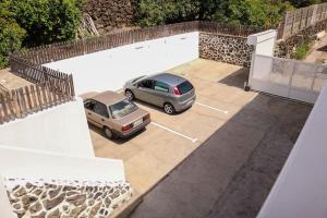zwei Autos auf einem Parkplatz neben einem Gebäude geparkt in der Unterkunft Inés (B): Relax y playa. in Breña Baja