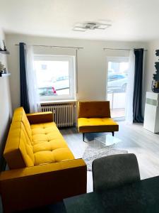 a living room with a yellow couch and two chairs at Zollernalb-Apartment G6 in Albstadt