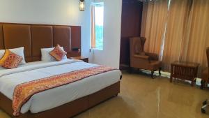 a bedroom with a large bed and a chair at Maya Heritage in Bodh Gaya