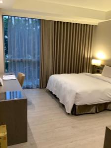 um quarto de hotel com uma cama e uma grande janela em Jin Shi Hu Hotel em Kaohsiung