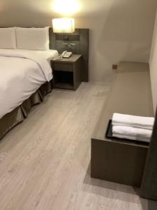 a hotel room with a bed and a desk with a phone at Jin Shi Hu Hotel in Kaohsiung