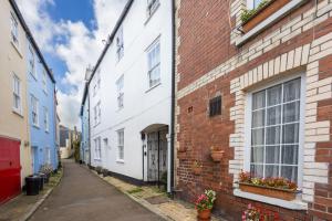 a narrow alley with buildings and potted plants at 3 Bell Court - Large Apartment close to Historic Market and Quay in Dartmouth