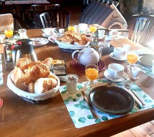 - une table avec du pain et des croissants dans des paniers dans l'établissement Chambres d'Hôtes La Fougeraie, à Malvières