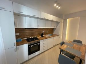 a kitchen with white cabinets and a table and a dining room at Luxury Wellness&Spa- Cortina North in Bucharest