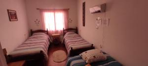 three beds in a room with a window at La Candelaria in Humahuaca