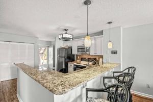 a kitchen with a counter with chairs and a counter top at 2nd Row Beach Condo, steps to the beach, with Pool in Myrtle Beach