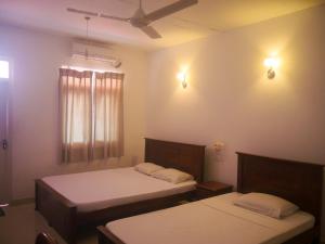 a bedroom with two beds and a ceiling fan at Visaka Hotel - Kataragama in Kataragama