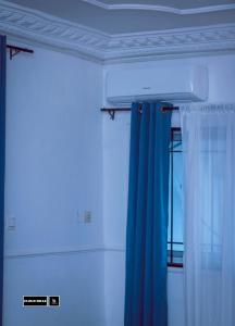 een kamer met een blauw gordijn en een raam bij CloudHill in Buea