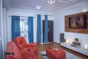 a living room with a red chair and blue curtains at CloudHill in Buea
