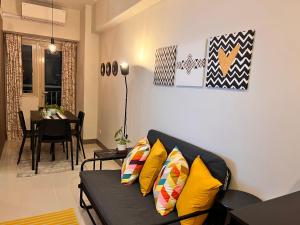 a living room with a black couch with yellow pillows at SMDC Coast Residences in Manila
