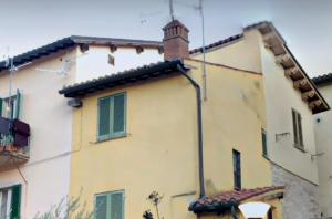 a yellow building with green shutters on it at Barbara rooms in Foligno