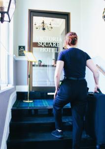 une femme debout sur les escaliers avec une valise dans l'établissement Victoria Square Hotel Clifton Village, à Bristol