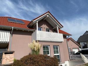 a pink house with a red roof with white flowers at Ferienwohnung Vogelsang in Laufenburg