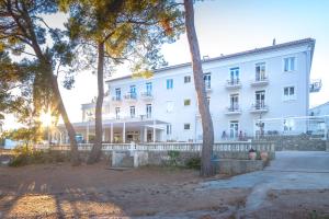 a large white building with trees in front of it at Hotel Bor in Krk