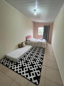 a bedroom with two beds and a rug at Kitnet ao lado do centro in Itabira