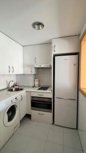 a white kitchen with a refrigerator and a dishwasher at Samaniego suite, AirPort, ifema turístico in Madrid