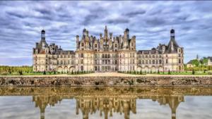 une réflexion sur les châteaux dans l'eau en face d'un château dans l'établissement Le Petit Nicolas - Centre historique de Blois - NETFLIX, JEUX, RETROJECTEUR, à Blois