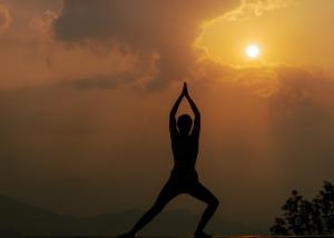 Una donna che fa una posa yoga davanti al tramonto di Hotel Annapurna View Sarangkot a Pokhara