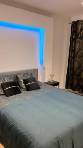 a bedroom with a large bed with a blue light at Maison jardin paisible 1 chambre in Mérignac
