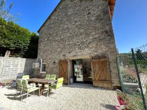 a patio with a table and chairs in front of a building at Chez Anabelle in Saint-Éloi