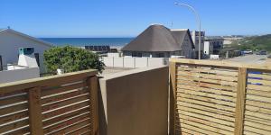 a wooden fence on a balcony with a view of the ocean at Secrets 2 at Waterkant 7 in Jeffreys Bay +14 photos