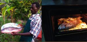 a man holding a plate of fish in an oven at SAFARI Lodge Location Bungalow in Cap Skirring