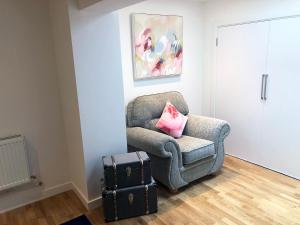 einen Stuhl mit einem rosa Kissen und einem Koffer in der Unterkunft Kings Road a new development with unique features in Newbury