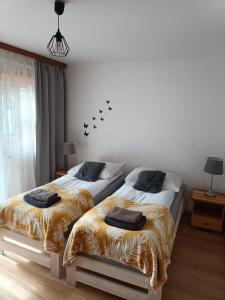 two beds sitting next to each other in a bedroom at Apartament Leśny in Supraśl