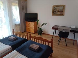 a bedroom with two beds and a desk with a television at Apartament Leśny in Supraśl