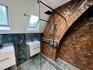 a bathroom with a brick wall and a glass shower at Modern City Centre Townhouse sleeps 10 & Parking in Manchester