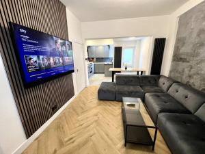 a living room with a couch and a flat screen tv at Modern City Centre Townhouse sleeps 10 & Parking in Manchester